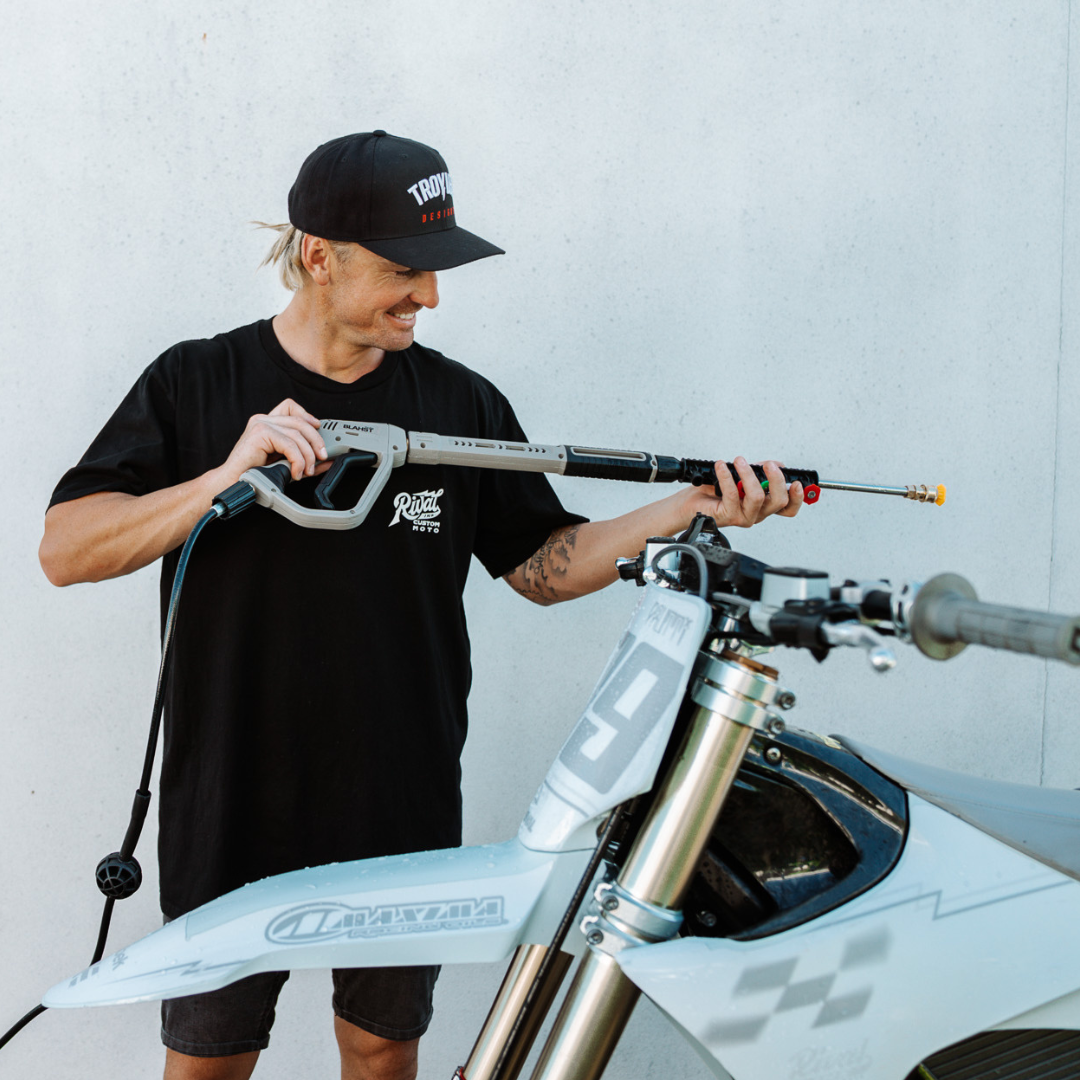 Man using a pressure washer to clean a dirt bike