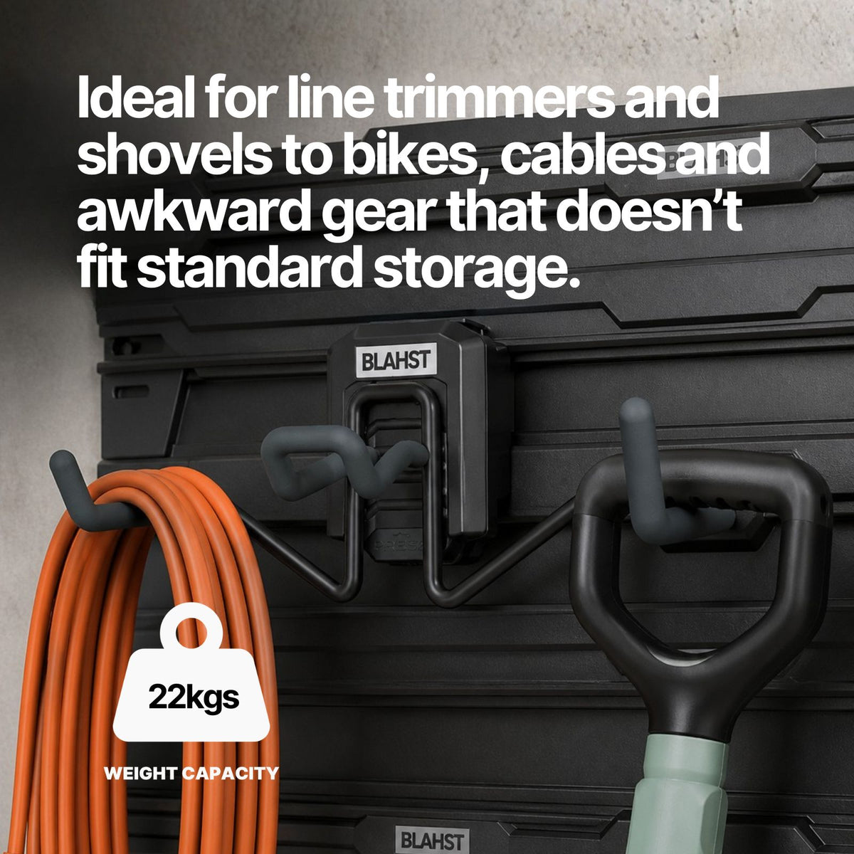 Orange cable and a shovel hanging from a BLAHST Modular Multi-Purpose Hook on a wall panel
